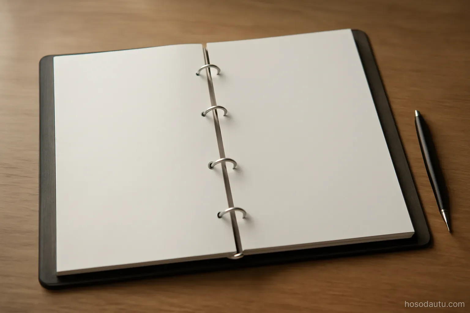 a neatly tabbed ring binder open flat on a desk beside a pen, overhead view, pages blank and unmarked