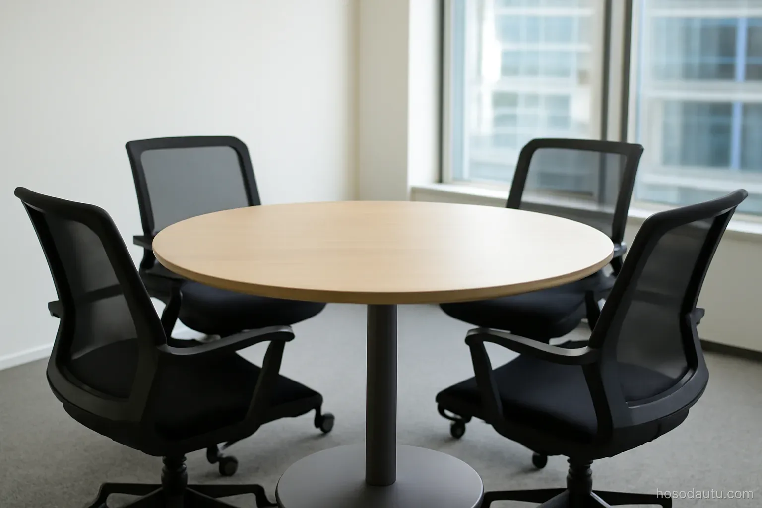 four empty chairs arranged around a round table in a bright meeting room, wide view, no papers or people